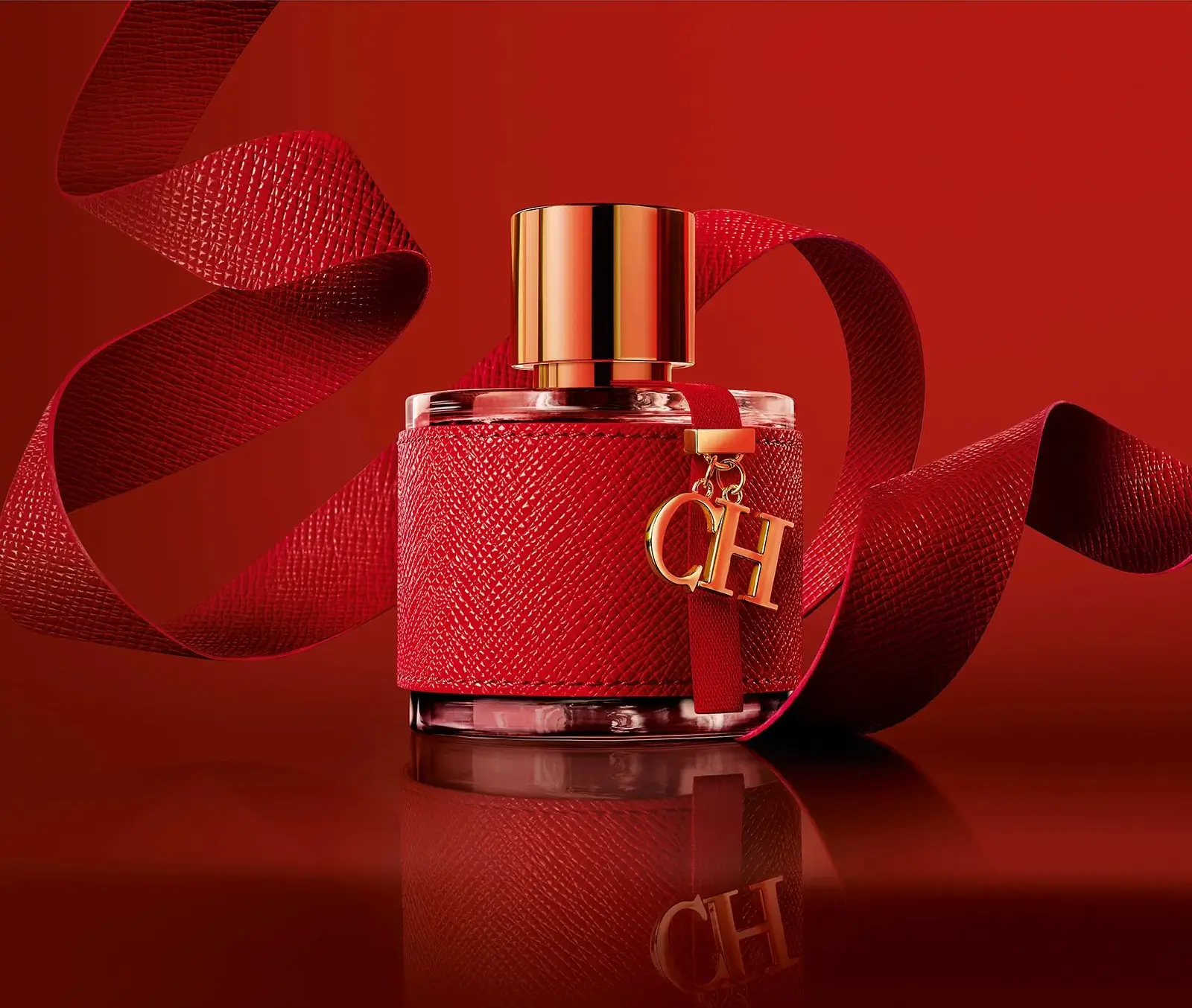 Frasco vermelho do CH Eau de Parfum da Carolina Herrera, com fita de tecido e medalhinha dourada, representando elegância clássica e estilo atemporal.