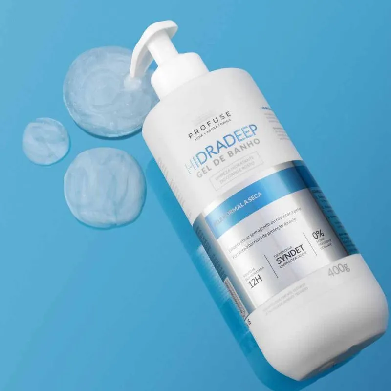 Frasco de Daily Profuse Sabonete Líquido Corporal em fundo azul com algumas gotas do produto próximas ao frasco.