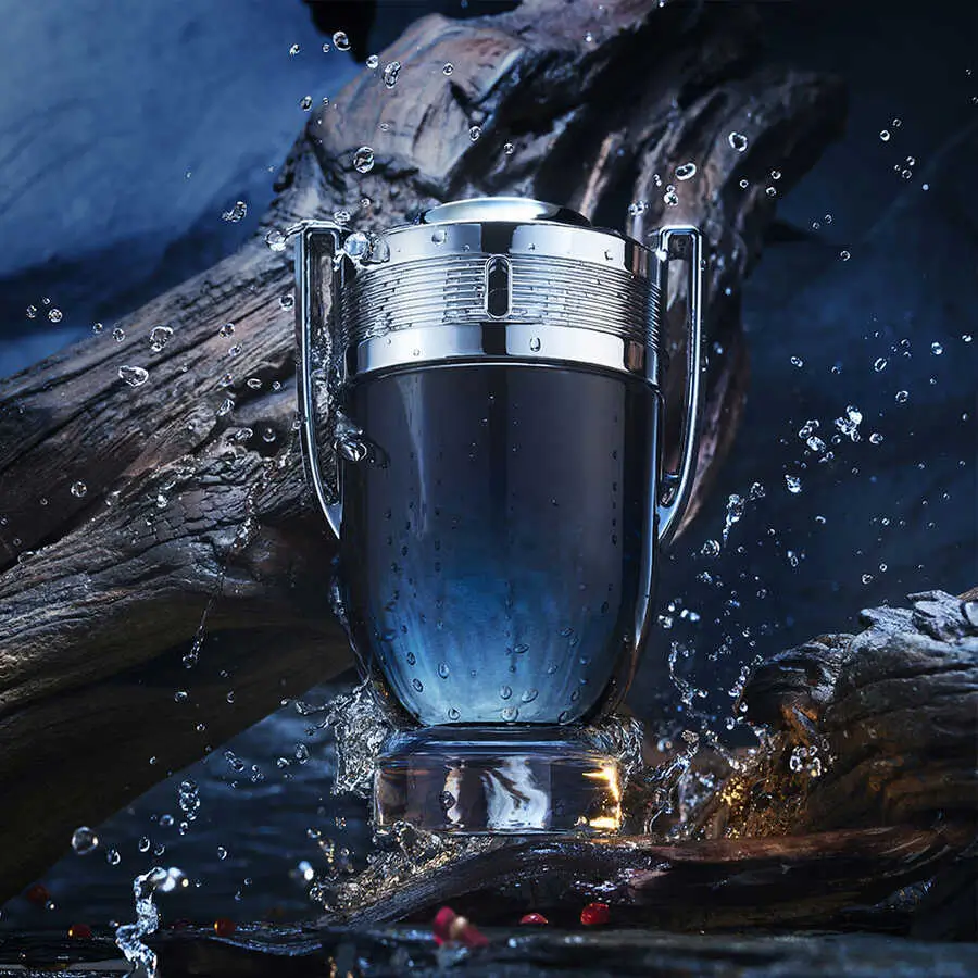 Frasco do perfume Paco Rabanne Invictus cercado por água e madeira, representando frescor, energia e masculinidade vencedora.